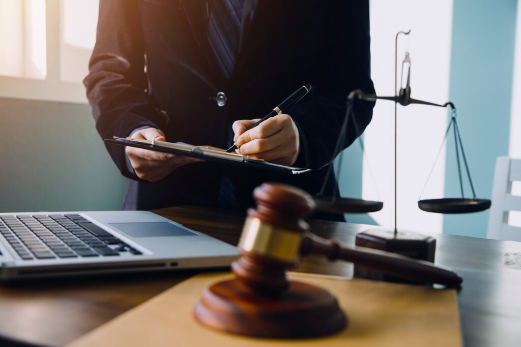 Lawyer reviewing legal documents with gavel, scales of justice, and laptop on desk, representing legal consultation and case preparation.